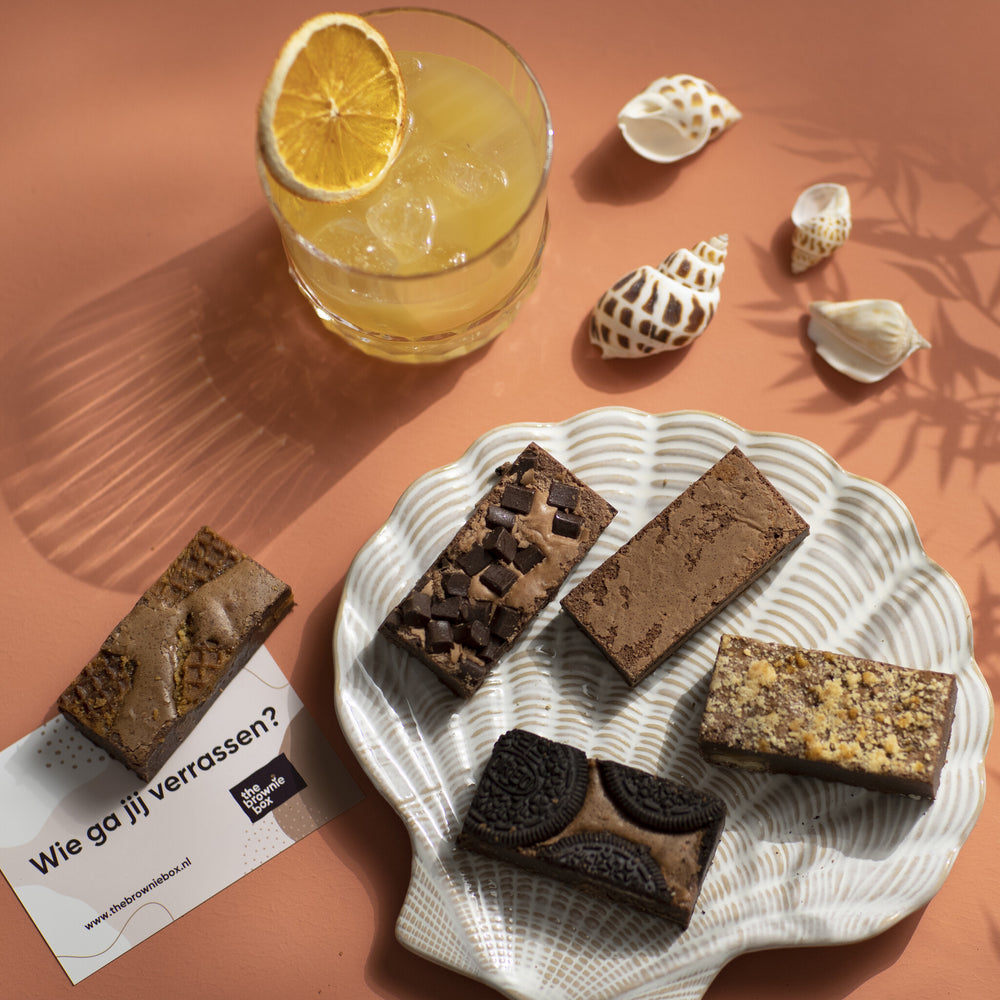 Stroopwafel brownies, originals brownies, karamel zeezout brownies en oreo brownies op een bordje met terracotta achtergrond