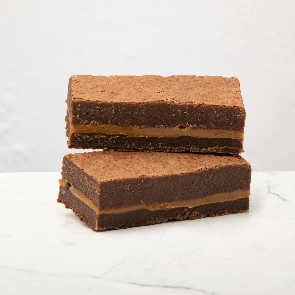 Twee karamel zeezout brownies op elkaar gestapeld. 