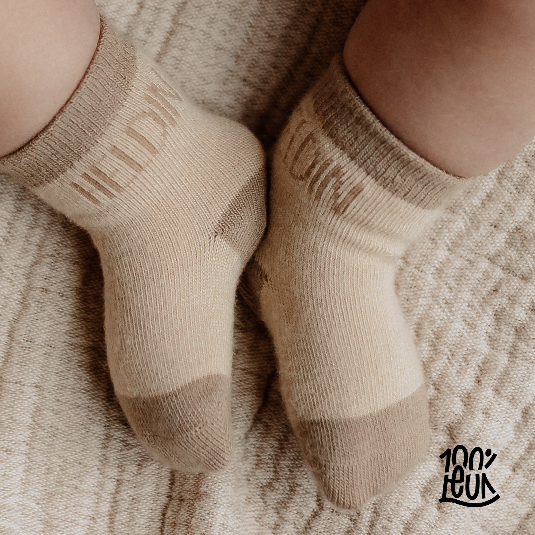 Sokjes met 'heldin' erop op een beige handdoek met babybeentjes