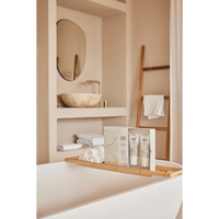 Therme Zen White Lotus geschenkset met douchegel en bodylotion op een houten badplank, naast een opgerolde witte handdoek. Een sfeervol wellnessmoment in een lichte badkamer met vrijstaand bad.