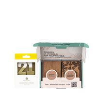 Een doosje met kaarsen erin met de cijfers 21. Daarbij een brownie box met 4 brownies erin op een witte achtergrond.